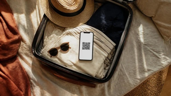 هاتف يعرض رمز QR لشريحة eSIM فوق حقيبة سفر قيد التجهيز